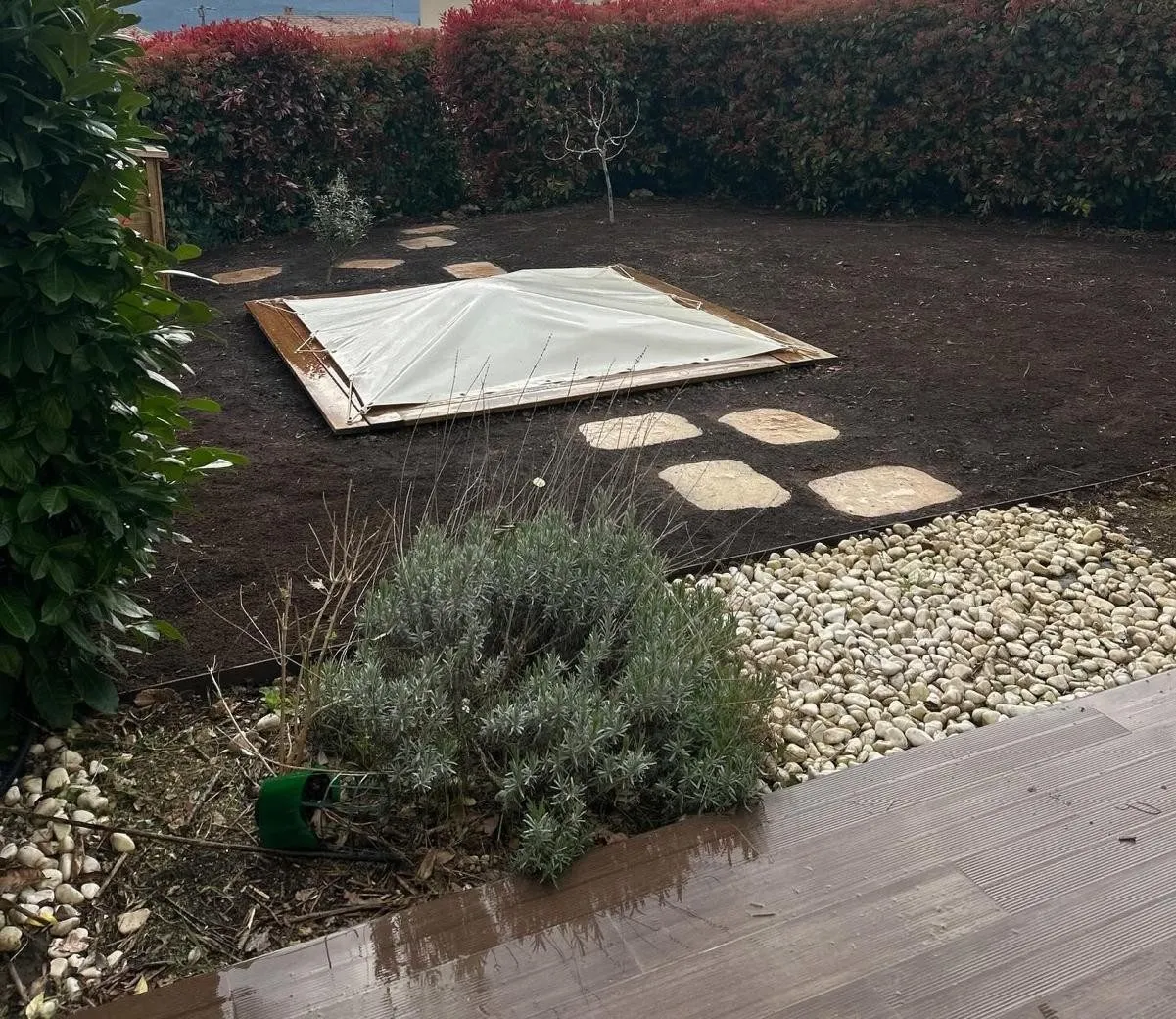 Terre préparée avec pas japonais et bordure de galets blancs sous la pergola, après travaux